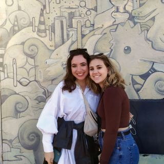 Cecilia Azar and companion pictured together in front of a mural.